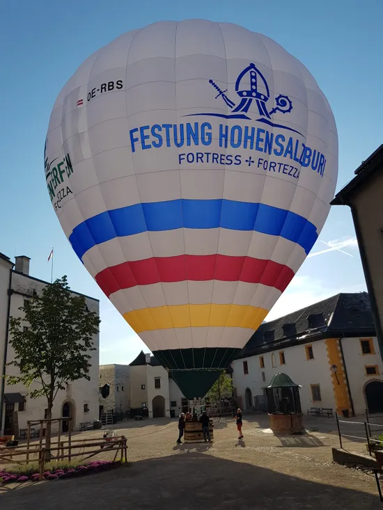 Heißluftballon mit Festung Hohensalzburg Logo im Burghof bei klarem Himmel