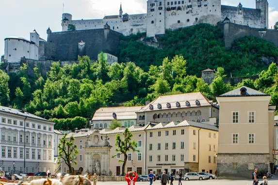 Blick auf die Festung Hohensalzburg über dem Kapitelplatz mit goldener Kugelskulptur in Salzburg, Österreich