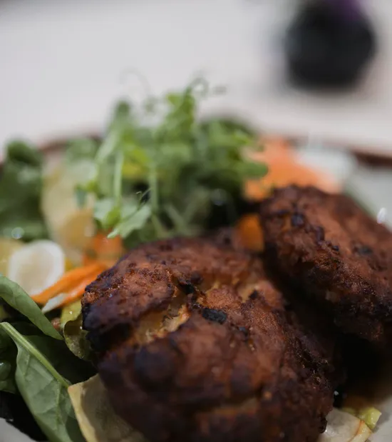 Knusprige vegane Frikadellen mit frischem gemischtem Salat auf Keramikteller serviert