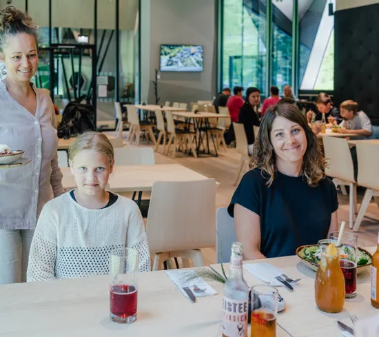 Famiglia che pranza in un ristorante moderno con bevande e insalate sul tavolo