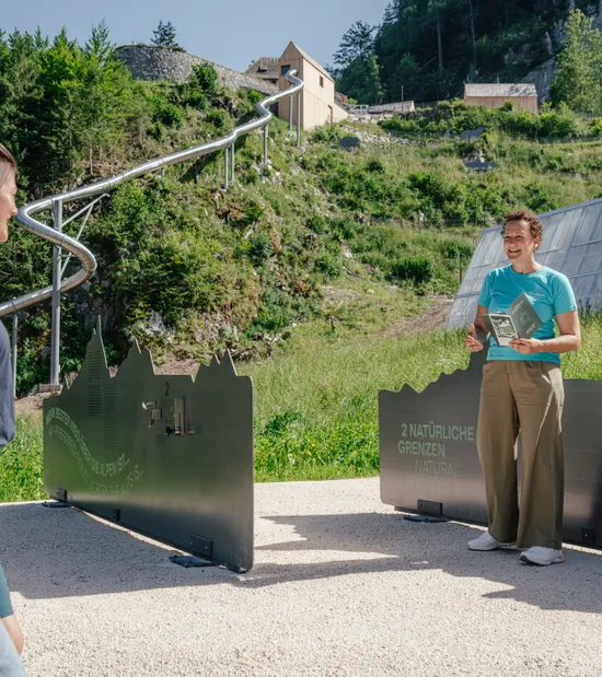 Führerin erklärt zwei Frauen ein Freiluft-Exponat über natürliche Grenzen im Gebirgspark