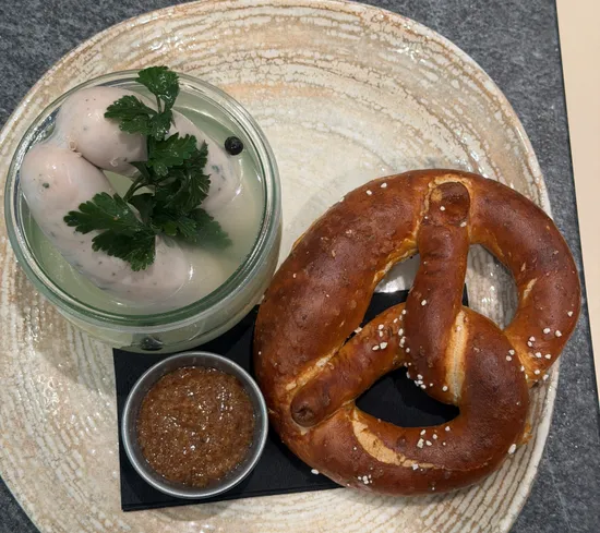 Bayerische Mahlzeit mit Brezel, Weißwürsten in Brühe und Senf auf einem Steinplatte