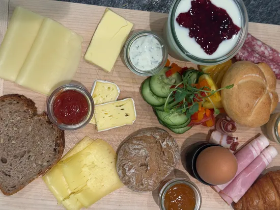 Frühstücksplatte mit Käse, Brot, Ei, Schinken, Joghurt mit Früchten und Gemüse
