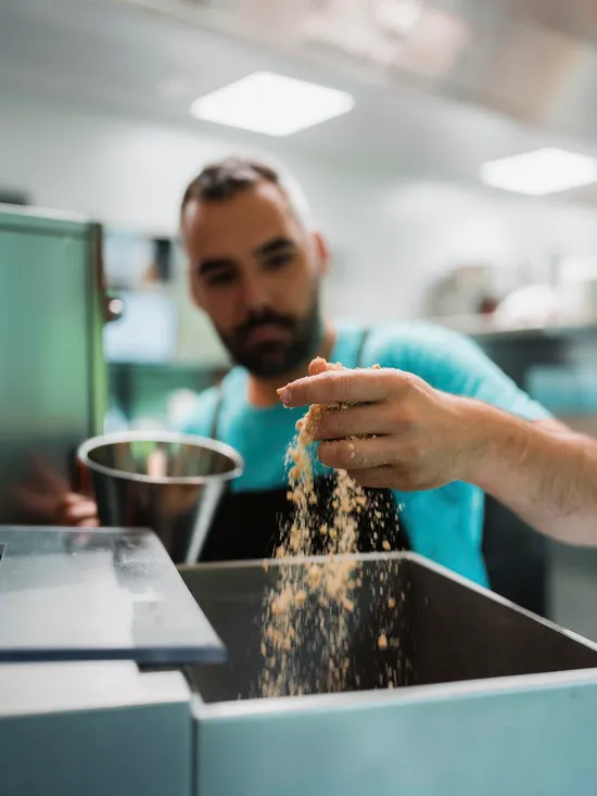 Chef adding breadcrumbs into a commercial food processor in a professional kitchen