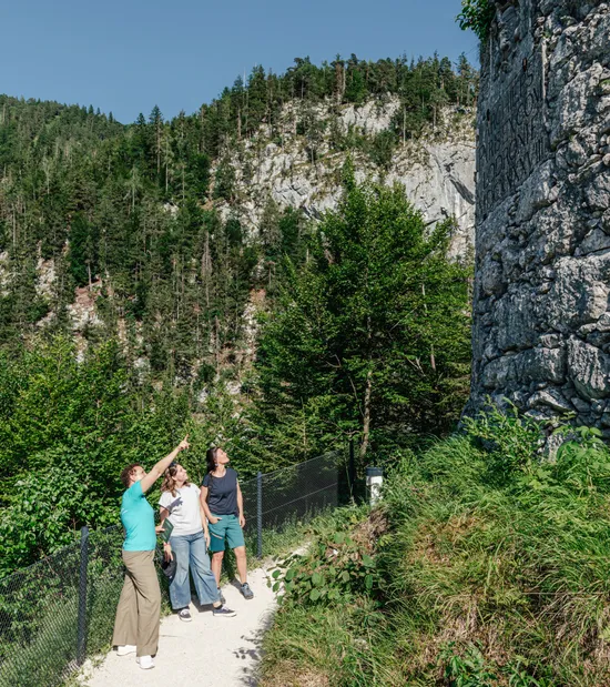 Hikers looking at a stone tower along a forest trail in the mountains