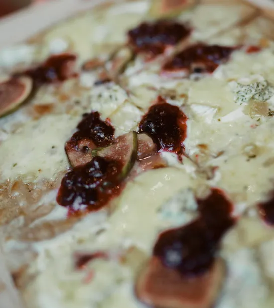 Gourmet-Fladenbrot mit geschmolzenem Käse, Feigen und dunklem Beerenkompott