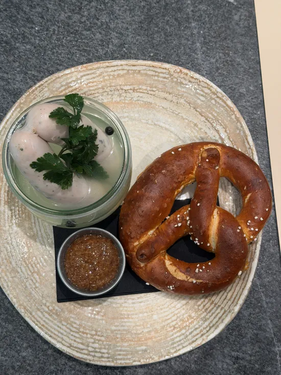 Bayerische Mahlzeit mit Brezel, Weißwürsten in Brühe und Senf auf einem Steinplatte