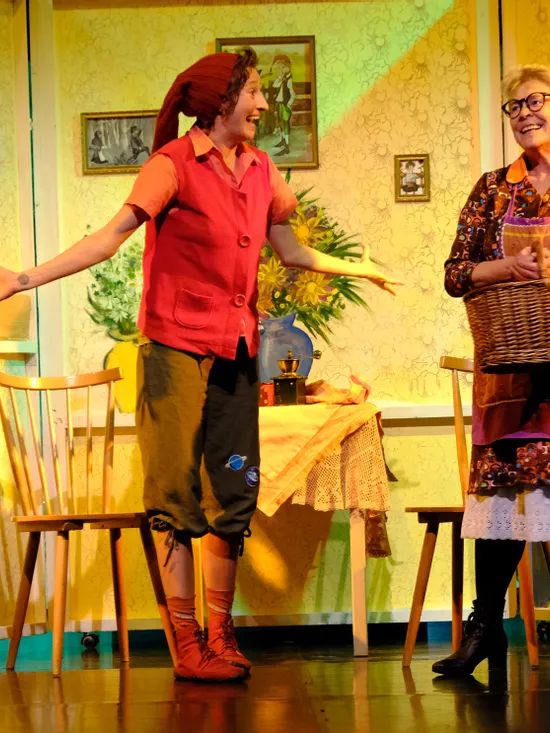 Zwei Frauen spielen auf einer hell erleuchteten Bühne in einer gemütlichen Vintage-Küche