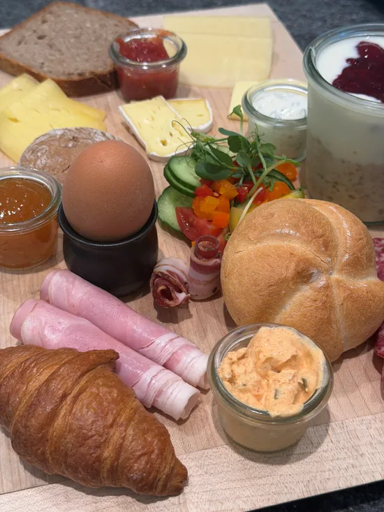 Assorted breakfast platter with cheese, meats, bread, egg, and yogurt