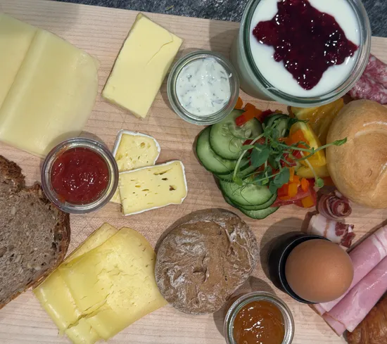 Frühstücksplatte mit Käse, Brot, Ei, Schinken, Joghurt mit Früchten und Gemüse