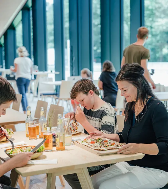 Familie genießt Mittagessen mit Pizza und Getränken in einem hellen modernen Restaurant