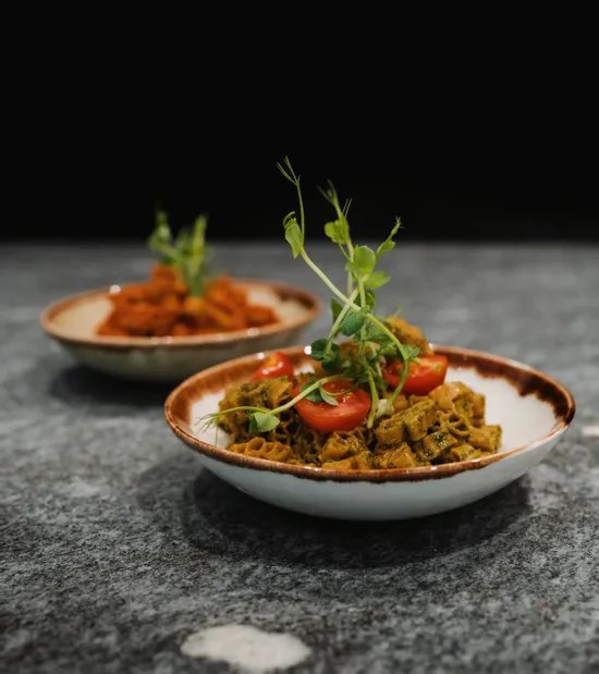 Veganer Nudelteller mit Cherrytomaten und Mikrogrün in rustikaler Keramikschale
