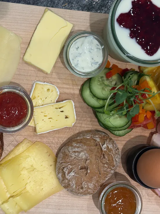 Breakfast platter with cheese, bread, egg, ham, yogurt with fruit, and vegetables
