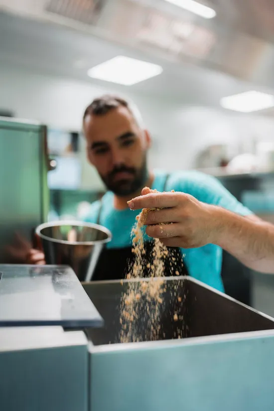 Koch gibt Semmelbrösel in eine gewerbliche Küchenmaschine in einer Profiküche