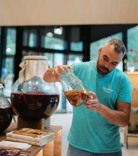 Mann betrachtet Kombucha-SCOBY in einem Glas bei einem Fermentationsworkshop