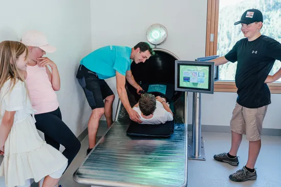 Kinder erkunden interaktive Rutschensimulation mit Betreuer im Indoor-Wissenszentrum
